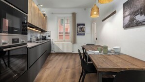 Eine moderne Küche mit Bosch-Ofen, Holzausstattung, einem Esstisch mit Stühlen und einer Hängelampe.