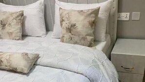 Un dormitorio con cama, almohadas, mesita de noche y cómoda.