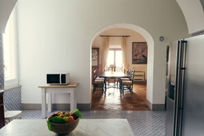 Eine Küche mit Essbereich, einer Mikrowelle auf einer Arbeitsplatte, einem Kühlschrank und einem Tisch mit Stühlen.