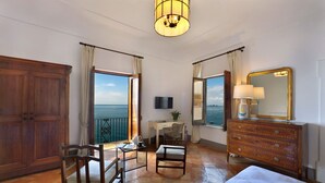 Camera d'albergo con un ampio armadio in legno, una scrivania con sedia, un letto, un comò e un grande specchio.