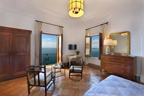 Ein Hotelzimmer mit großem Holzschrank, einem Schreibtisch mit Stuhl, einem Bett, einer Kommode und einem großen Spiegel.