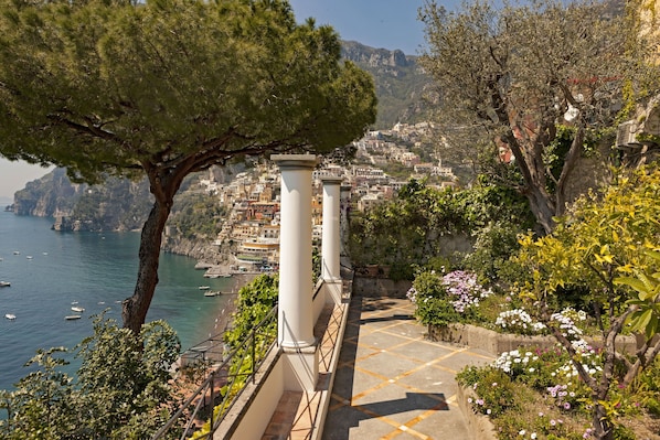 Eine Küstenstadt mit einer Steintreppe, Bäumen und Blick auf das Meer und die Bebauung.