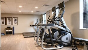 A gym with multiple treadmills, a bench, and a wall clock.