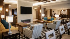 A modern hotel lobby with a fireplace, seating area, and a bar.