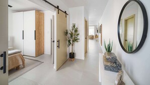 A modern hallway with a sliding door, a potted plant, a mirror, and a tiled floor. - Walk to Beach, New Elegant 2BR Villa with Pool! (Lower Carlton)