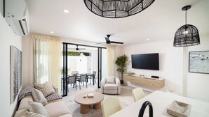 A modern living room with a sofa, coffee table, and TV. - Walk to Beach, New Elegant 2BR Villa with Pool! (Lower Carlton)