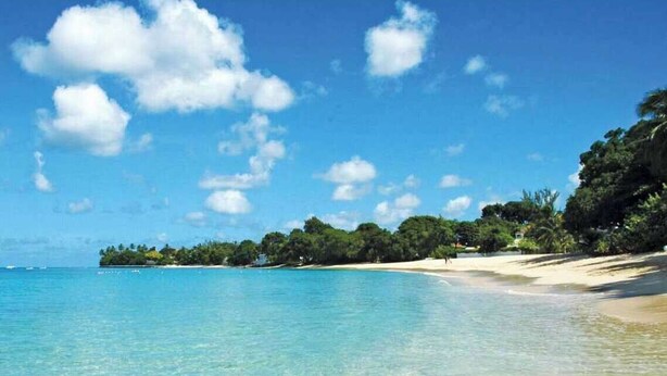 A beach with clear turquoise water, a sandy shore, and dense green foliage in the background. - Walk to Beach, New Elegant 2BR Villa with Pool! (Lower Carlton)