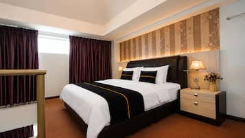 A hotel room with a large bed, a bedside table with a lamp, a nightstand, and a window with curtains.