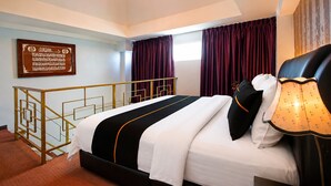 Una habitación de hotel con cama, candelabro, ventana con cortinas y un cartel en la pared.