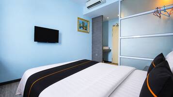 A hotel room with a bed, a television, a wardrobe, and an air conditioning unit.