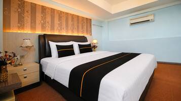 A hotel room with a large bed, a nightstand with a lamp, and a wall-mounted air conditioner.