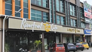 Un edificio con un letrero de Riverfront Cafe, un hotel 4th of July, y varios letreros comerciales, incluyendo Panasonic.