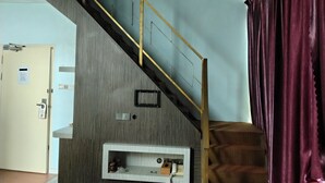 Una escalera con barandilla metálica, un teléfono en la pared y una puerta con un cartel.