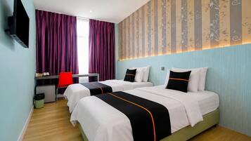 A hotel room with two beds, a desk, a chair, and a TV mounted on the wall.