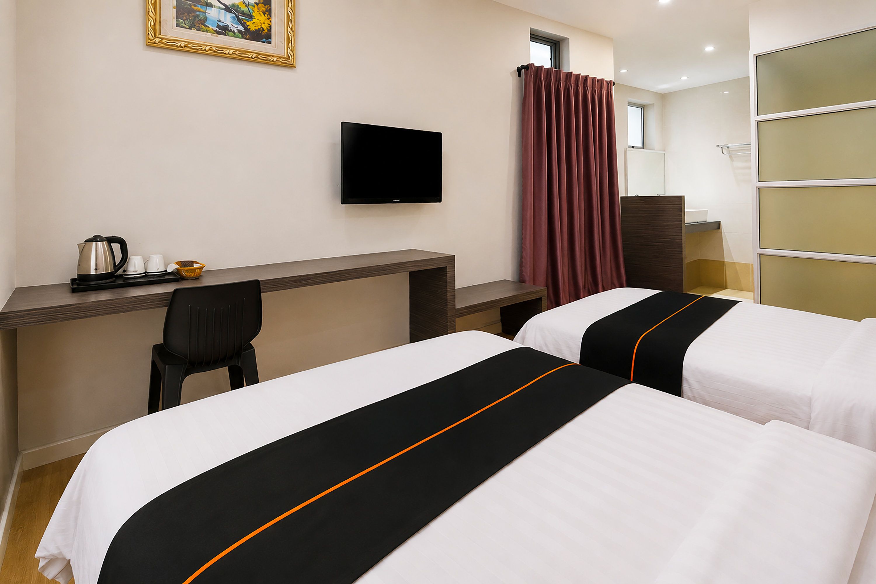 A hotel room with two beds, a desk, a chair, a television, and a window with curtains.