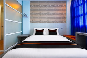 A hotel room with a bed, a nightstand, a wall with a floral pattern, and a blue curtain. - Collection O Near Tanjung Batu Formerly 4orty Inn (Bintulu)