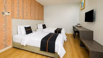 A hotel room with two beds, a desk, a chair, a flat-screen TV, and a wooden floor.