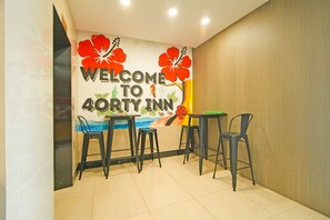 A reception area with a wall mural, a table, and four chairs. - Collection O Near Tanjung Batu Formerly 4orty Inn (Bintulu)
