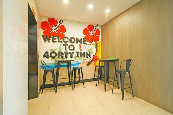 A reception area with a wall mural, a table, and four chairs. - Collection O Near Tanjung Batu Formerly 4orty Inn (Bintulu)