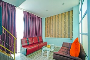 A living room with a red sofa, a smaller armchair, a glass coffee table, and a window with striped curtains. - Collection O Near Tanjung Batu Formerly 4orty Inn (Bintulu)