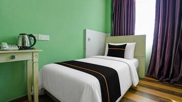 A hotel room with a bed, a desk, a telephone, and a kettle.