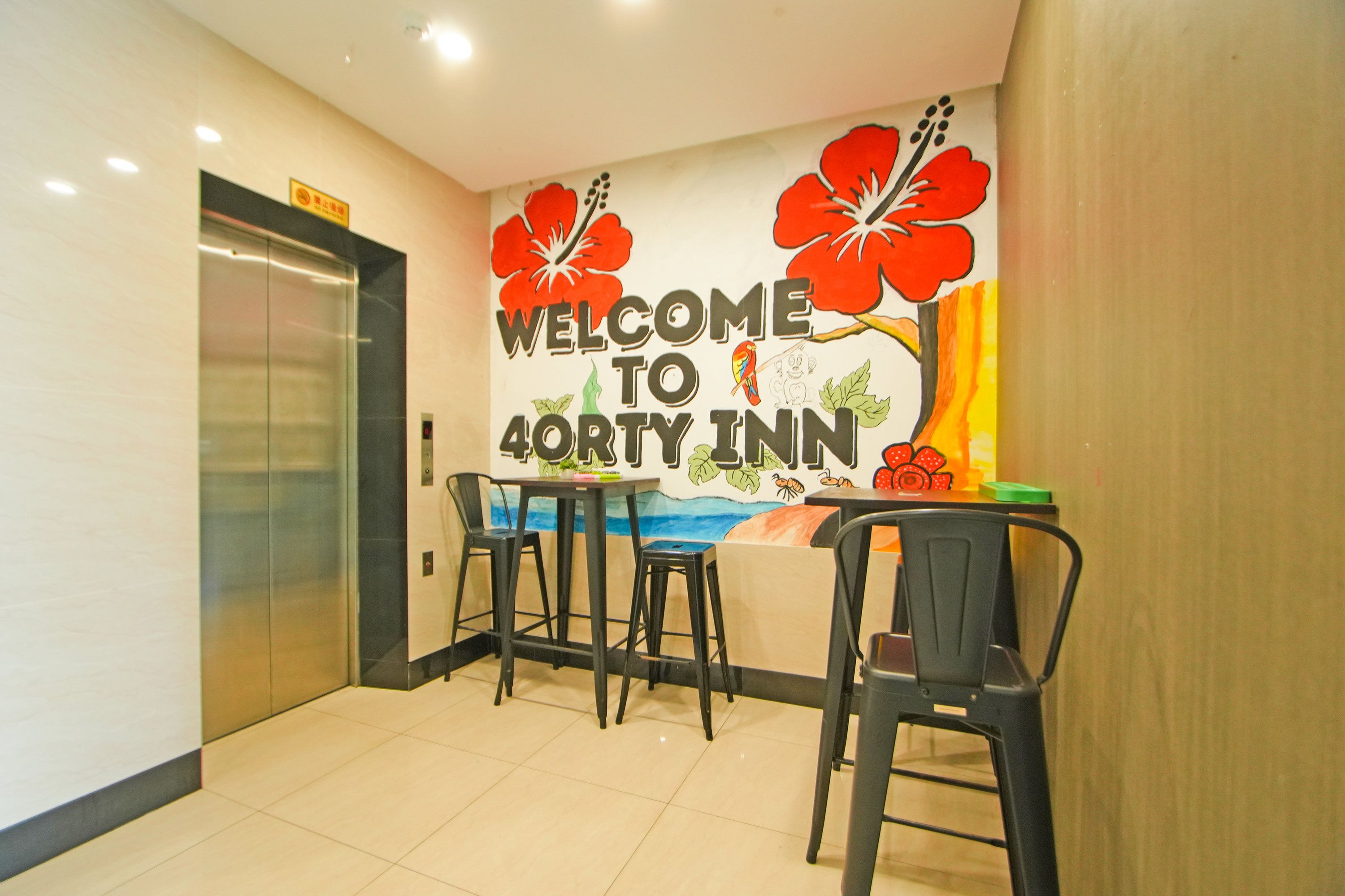 Un vestíbulo de hotel con un letrero que dice 'Welcome to 40th Inn', un mostrador de recepción, dos taburetes de bar y un ascensor.