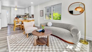 Uma sala de estar moderna com sofá, mesa de centro e área de jantar com cadeiras e mesa.