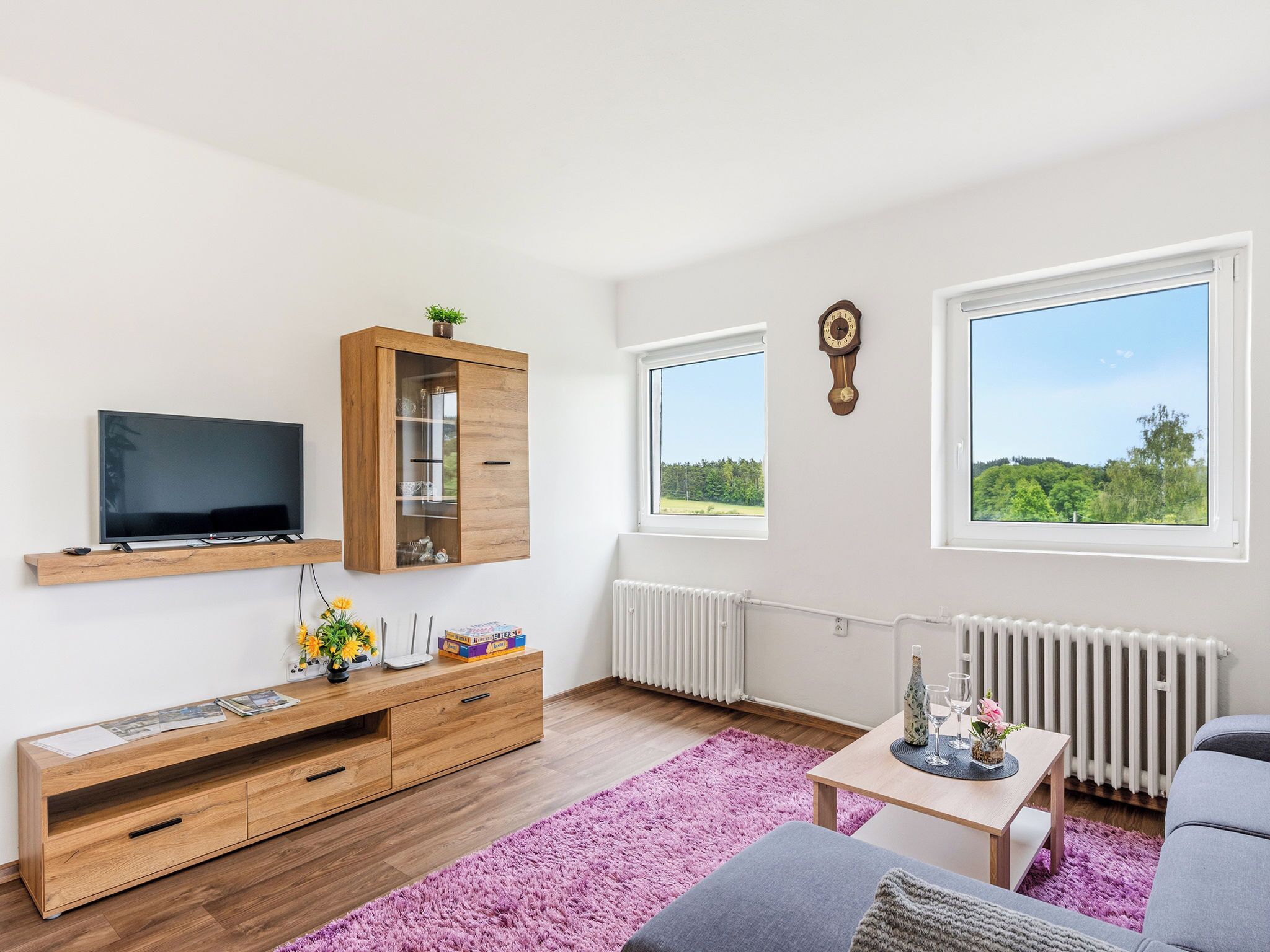 Un salon moderne avec un téléviseur à écran plat, un meuble en bois et un canapé confortable.