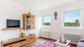 Un salon moderne avec un téléviseur à écran plat, un meuble en bois et un canapé confortable.