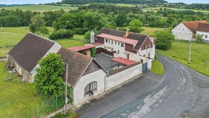 A rural building with a red roof, surrounded by green fields and hills. - Happy Home by Interhome (Hradesice)