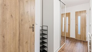 A hallway with wooden flooring, a sliding door, and a metal shelf unit. - Happy Home by Interhome (Hradesice)