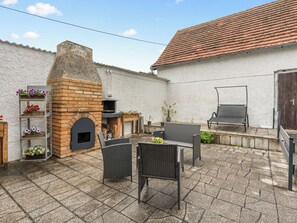 A patio with a brick oven, outdoor furniture, and flower planters.