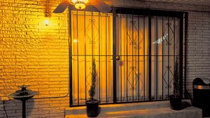 A brick building with a metal gate, a potted plant, and a small table.