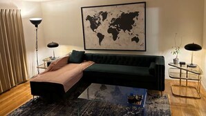 A modern living room with a sofa, a glass coffee table, a world map on the wall, and two lamps.