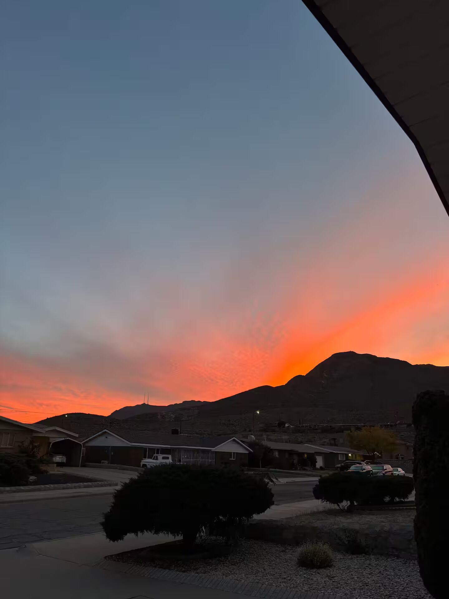 A residential area with houses, a parking lot, and a mountain in the background.