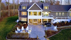 Une maison à deux étages dotée d’un patio couvert, d’un espace salon extérieur et d’un foyer.
