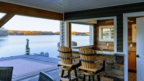 Une terrasse au bord du lac, avec des fauteuils Adirondack, un quai et une vue sur le lac et la forêt.