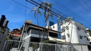 A gated residential area with a clear sky, power lines, and a building with a modern design. - Pousada santa Barbara (Florianópolis)