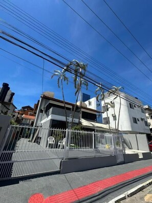 Área residencial murada com céu claro, linhas de energia e um edifício de design moderno.