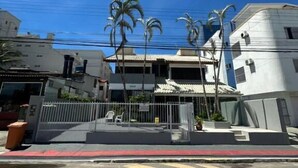 A street view with buildings, palm trees, and a pedestrian crossing. - Pousada santa Barbara (Florianópolis)