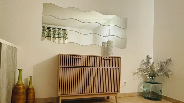 A room with a wooden cabinet, a mirror, and two vases on the floor. - Charming renovated studio 2 steps from the sea - Secure residence with all comforts (Sète)