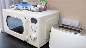 A compact kitchenette with a microwave, toaster, and a small storage container with kitchen items. - Bayview Aparthotel by Guestz (Morecambe)