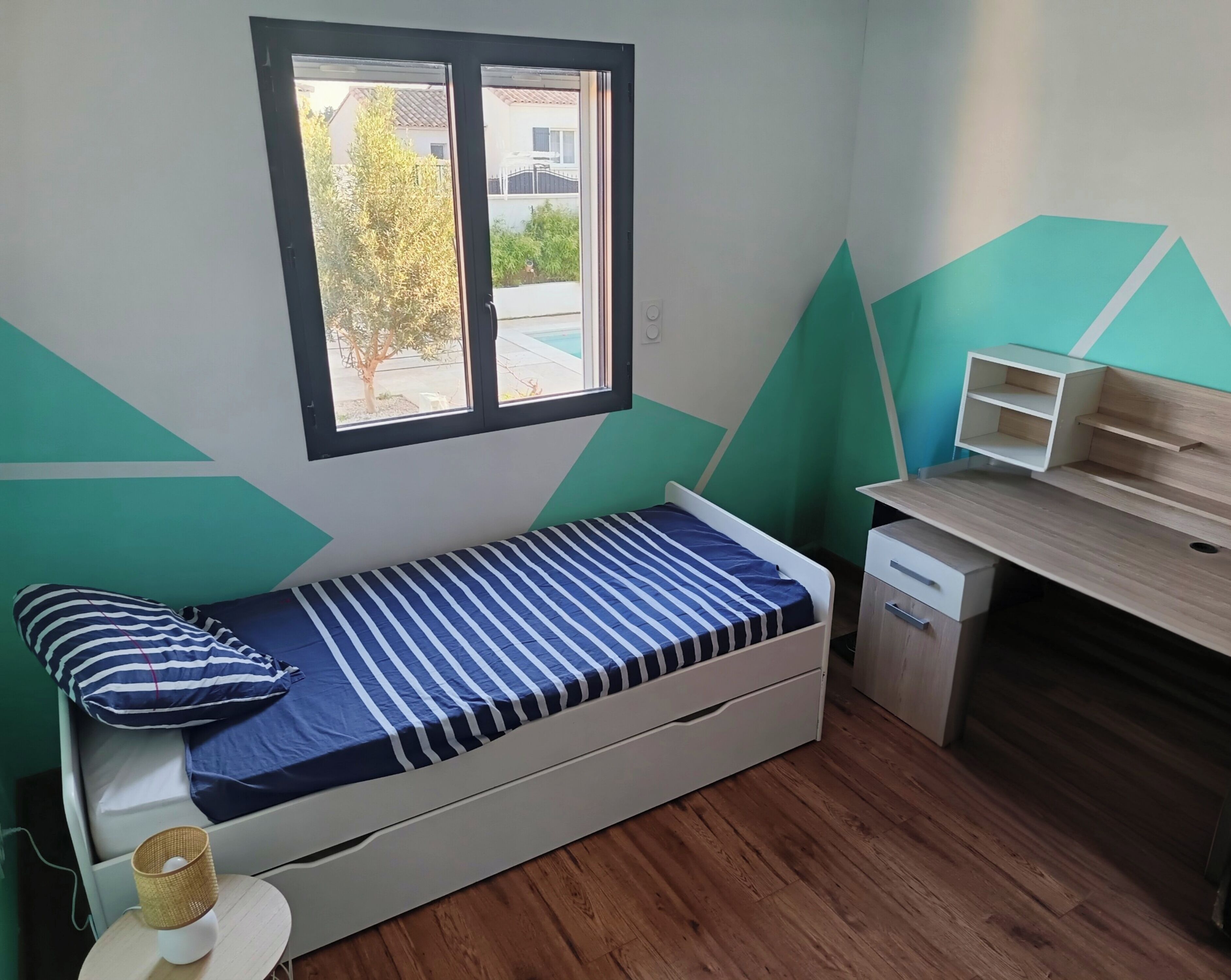 A small room with a bed, a desk, and a window.