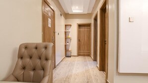 A hallway with a tufted chair, wooden doors, and a shelf unit. - The Shortlet Ahvi (Lekki)