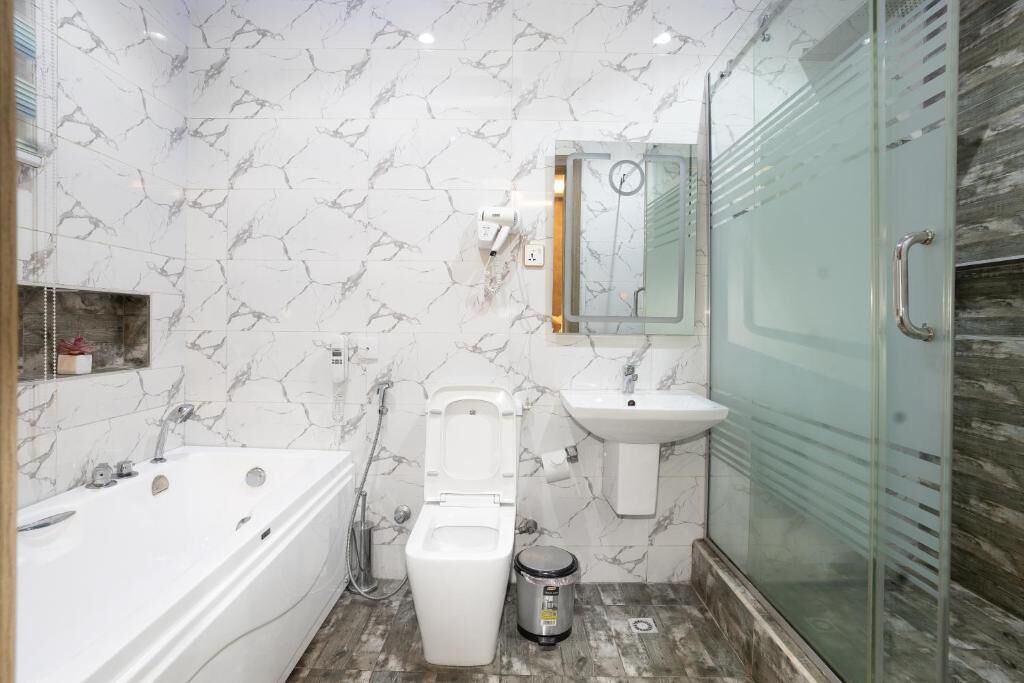 A bathroom with a bathtub, toilet, sink, and glass shower enclosure.