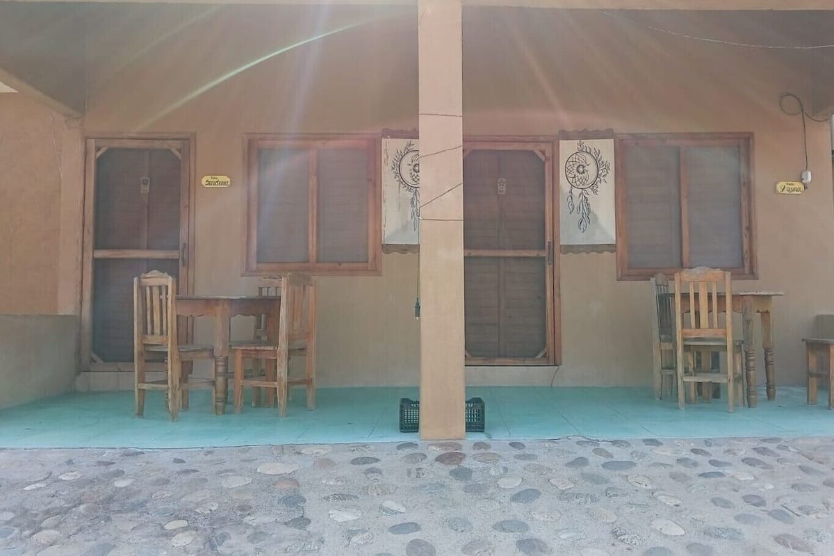 A building with two wooden doors, a covered porch, and a tiled floor.