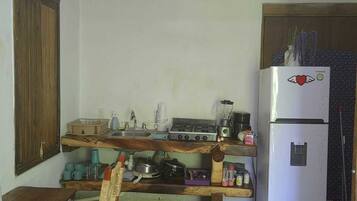 Una cocina con una mesa de madera, una silla, un refrigerador y un adorno colgante.