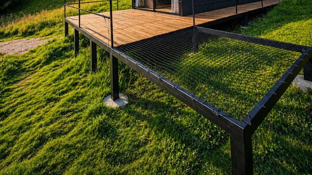 A modern cabin with a glass door, a wooden deck, and a metal railing. - Basecamp A Boutique Cabin Experience in the Wild (Carmen de Carupa)