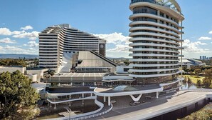 Un hotel moderno con una facciata curva, numerosi balconi e un cortile centrale.