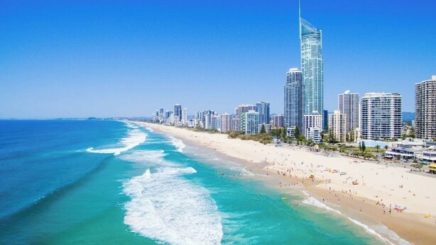 Paesaggio costiero urbano con un grattacielo imponente, spiaggia e edifici residenziali.